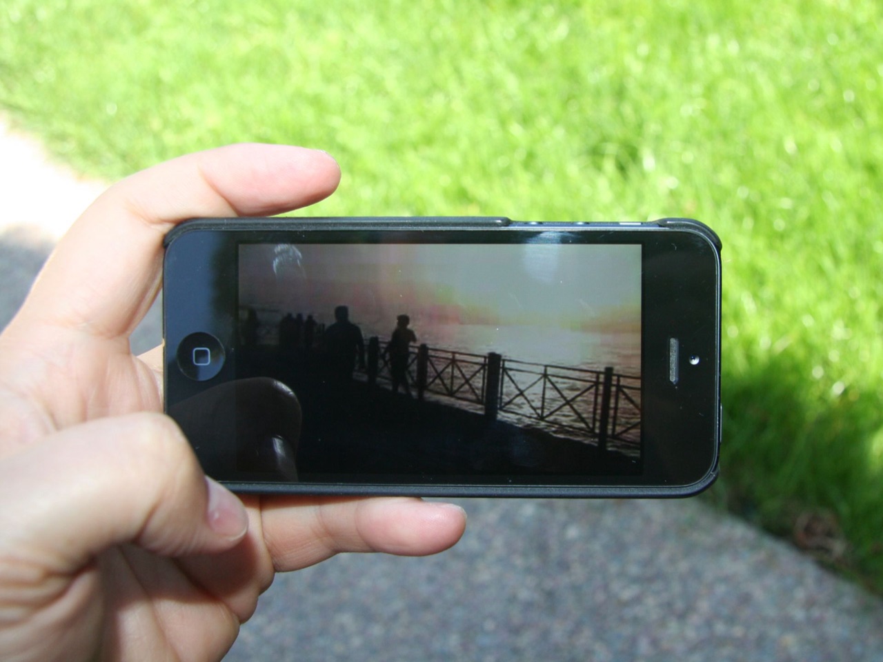 Bàn tay cầm điện thoại đang phát video ngoài trời